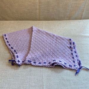Crocheted purple baby blanket with ribbon around border.
